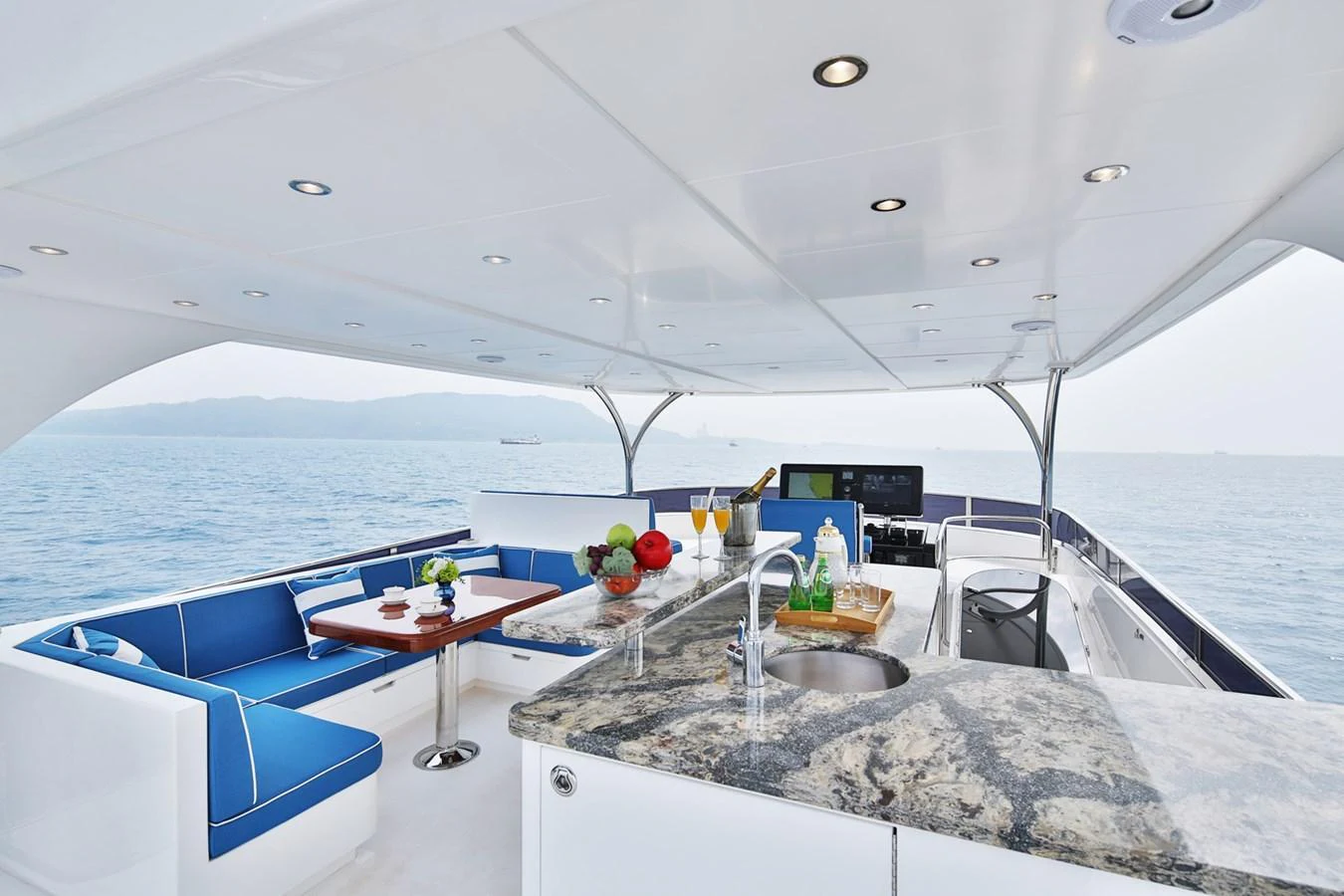 The flybridge features a luxurious seating area with a dining table and a well-equipped wet bar, perfect for entertaining guests while enjoying the sea view. aboard JOHNSON 83' FLYBRIDGE W/HYDRAULIC PLATFORM Yacht for Sale