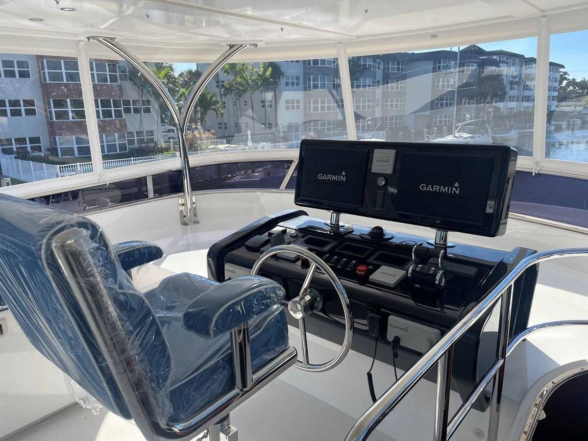 The helm station features modern navigation equipment and a comfortable captain's chair with a view of the surroundings. aboard JOHNSON 83' FLYBRIDGE W/HYDRAULIC PLATFORM Yacht for Sale