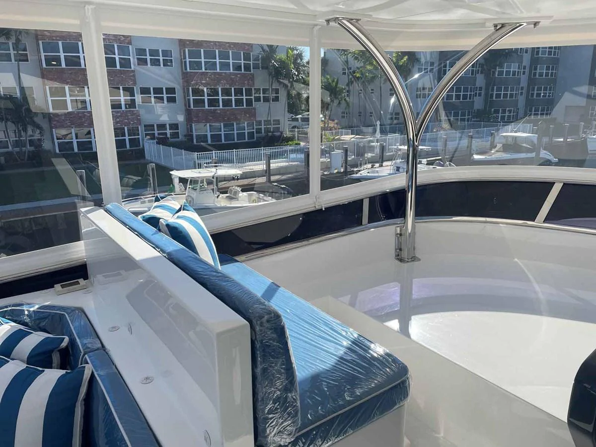 The flybridge offers a comfortable seating area with striped cushions and a view of the marina. aboard JOHNSON 83' FLYBRIDGE W/HYDRAULIC PLATFORM Yacht for Sale