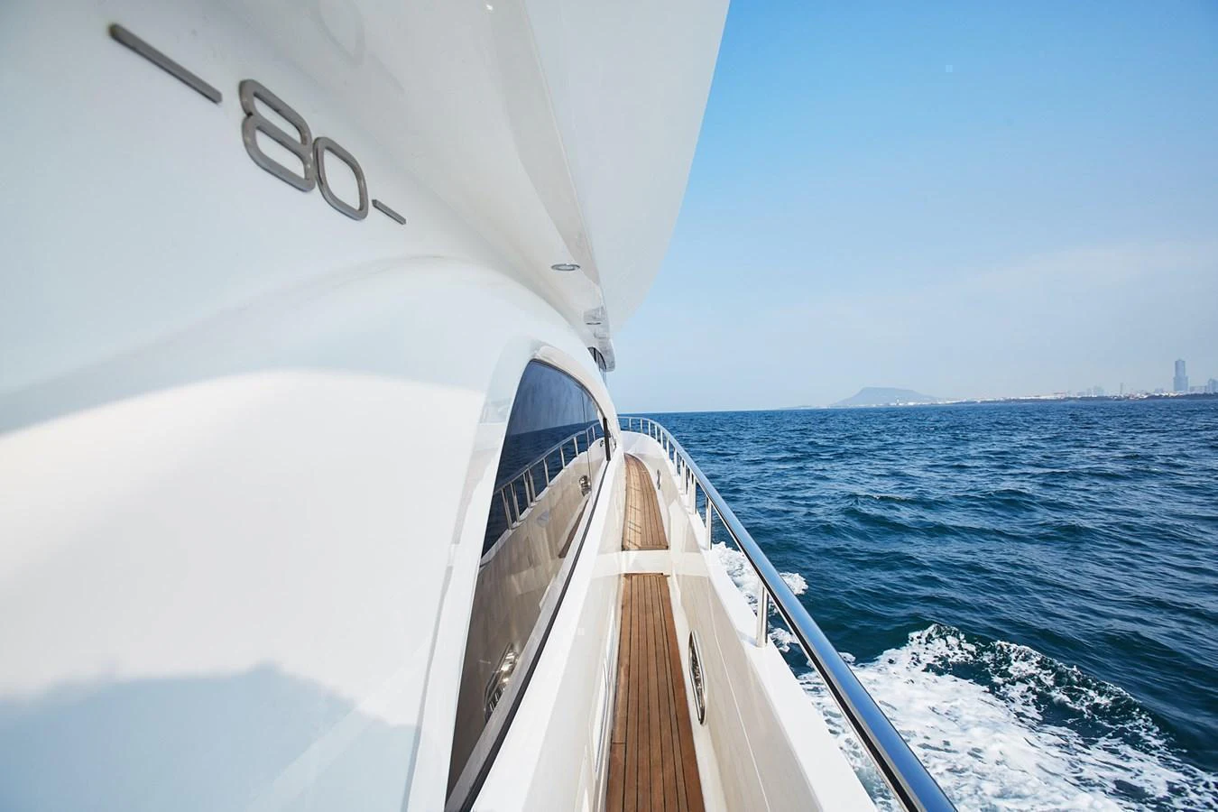 The yacht glides smoothly over the water, showcasing its sleek design and luxurious deck. aboard JOHNSON 83' FLYBRIDGE W/HYDRAULIC PLATFORM Yacht for Sale