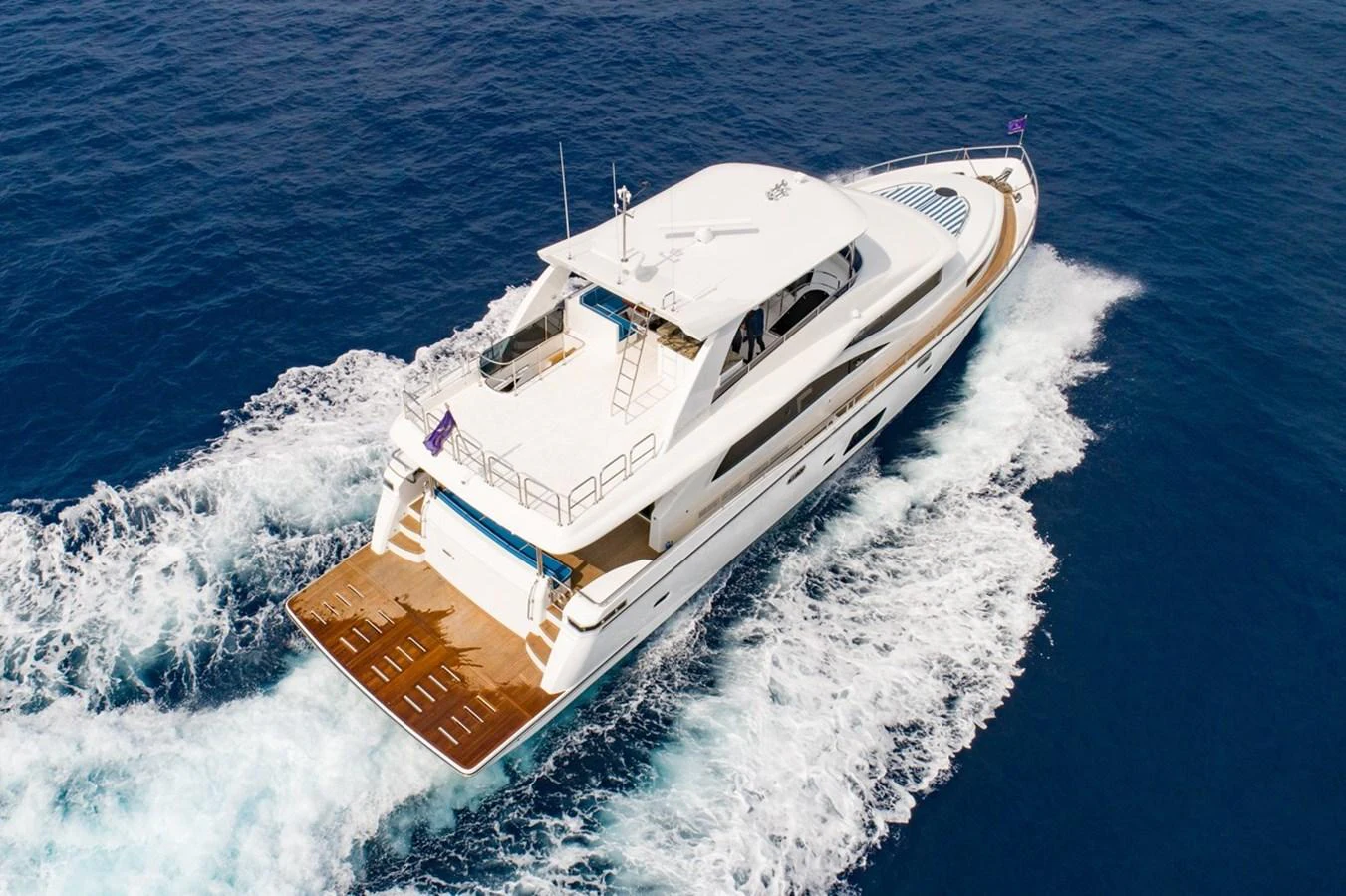 A sleek yacht cruises through the open water, showcasing its elegant design and spacious deck. aboard JOHNSON 83' FLYBRIDGE W/HYDRAULIC PLATFORM Yacht for Sale