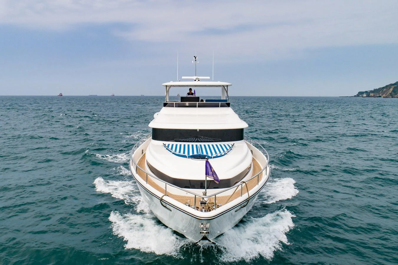 A sleek yacht cruises forward on open waters, showcasing its elegant design and spacious deck. aboard JOHNSON 83' FLYBRIDGE W/HYDRAULIC PLATFORM Yacht for Sale