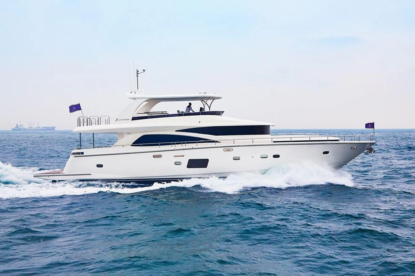 A sleek and modern yacht cruising on the open sea. aboard JOHNSON 83' FLYBRIDGE W/HYDRAULIC PLATFORM Yacht for Sale