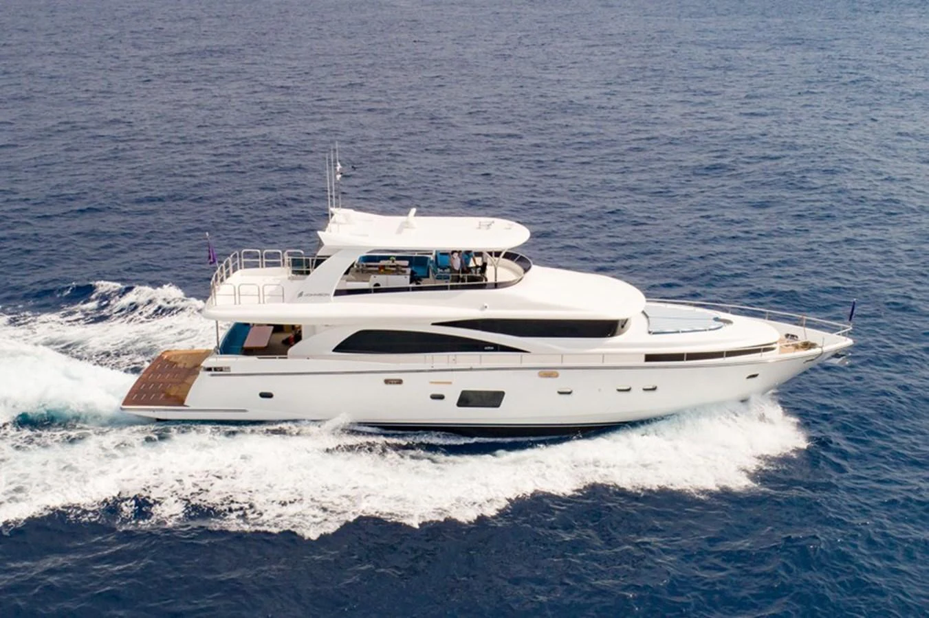 A sleek yacht cruises through the open water, showcasing its elegant design and spacious decks. aboard JOHNSON 83' FLYBRIDGE W/HYDRAULIC PLATFORM Yacht for Sale