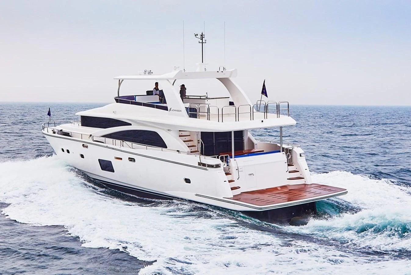 This elegant yacht cruises smoothly on the open sea, showcasing its sleek design and spacious aft deck. aboard JOHNSON 83' FLYBRIDGE W/HYDRAULIC PLATFORM Yacht for Sale