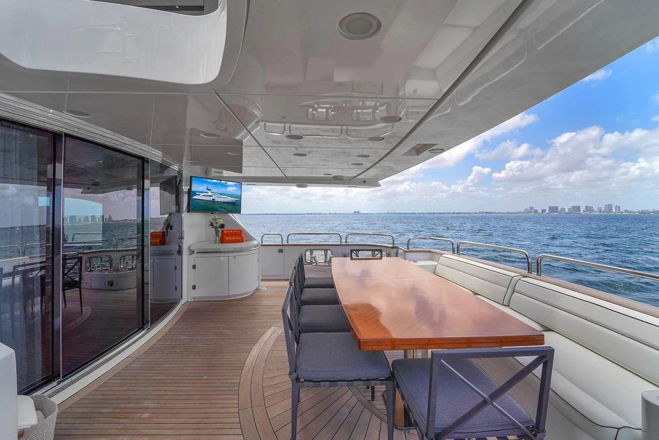 The aft deck features a spacious dining area with a polished wooden table and comfortable seating, perfect for enjoying meals with a view of the sea. aboard AZIMUT GRANDE 105 Yacht for Sale