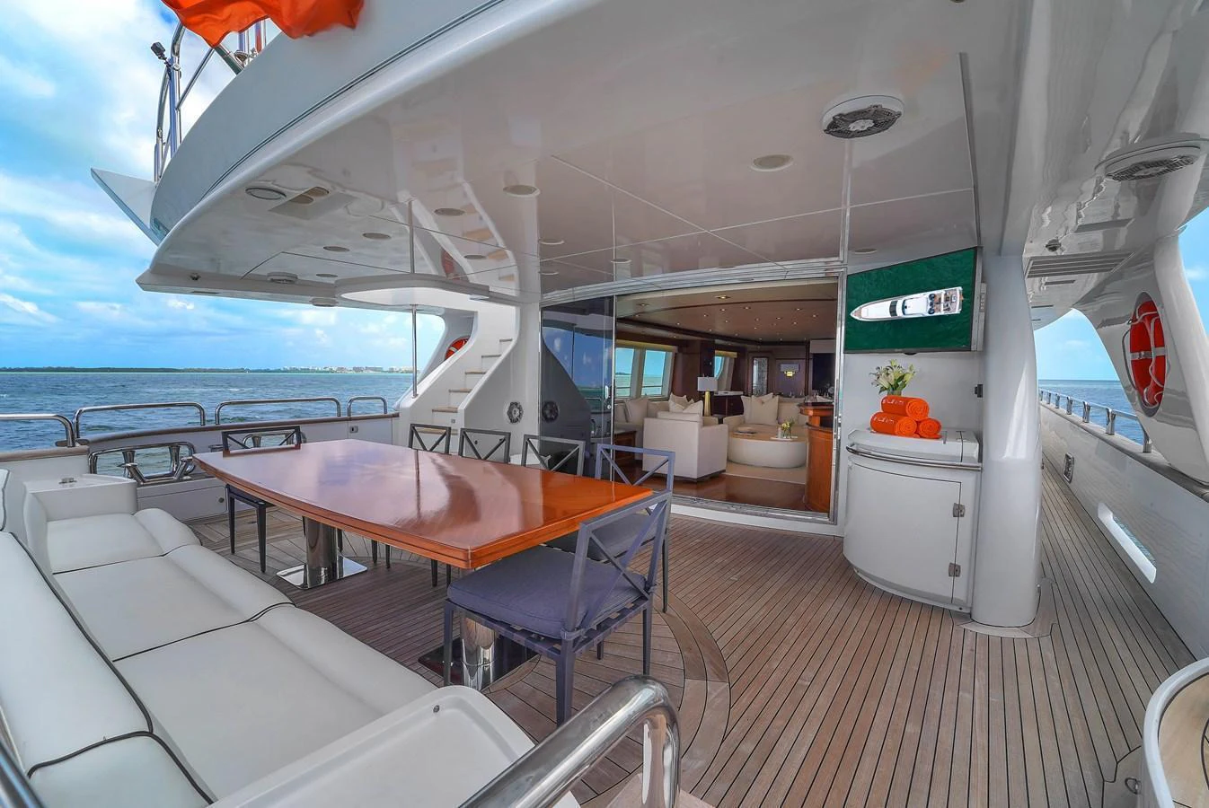 The aft deck features a spacious dining area with a view of the luxurious interior through sliding glass doors. aboard AZIMUT GRANDE 105 Yacht for Sale