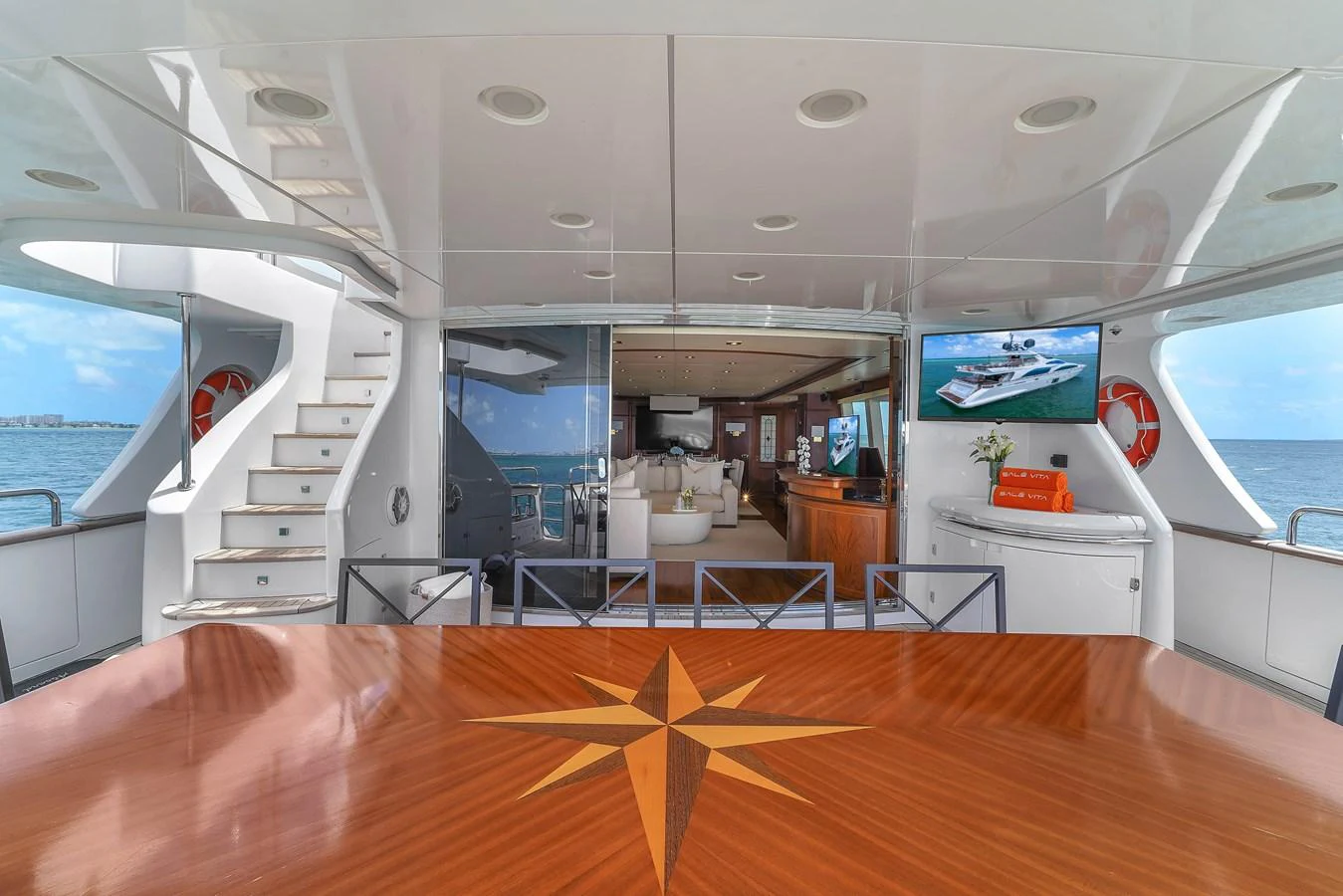The aft deck offers a spacious and inviting area with a beautiful wooden table and easy access to the interior living space. aboard AZIMUT GRANDE 105 Yacht for Sale