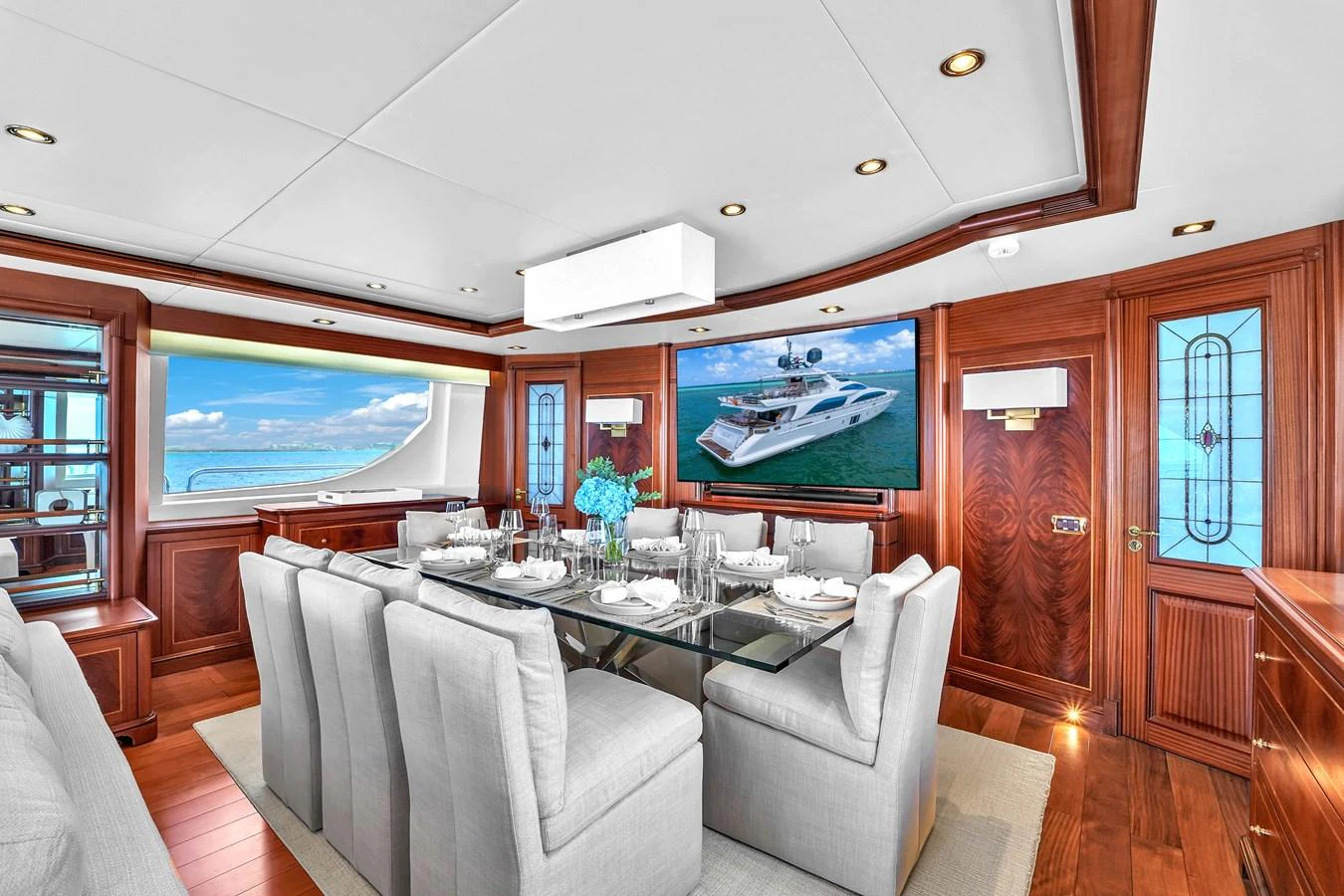 The yacht's dining area features elegant seating and a large screen displaying a yacht image. aboard AZIMUT GRANDE 105 Yacht for Sale