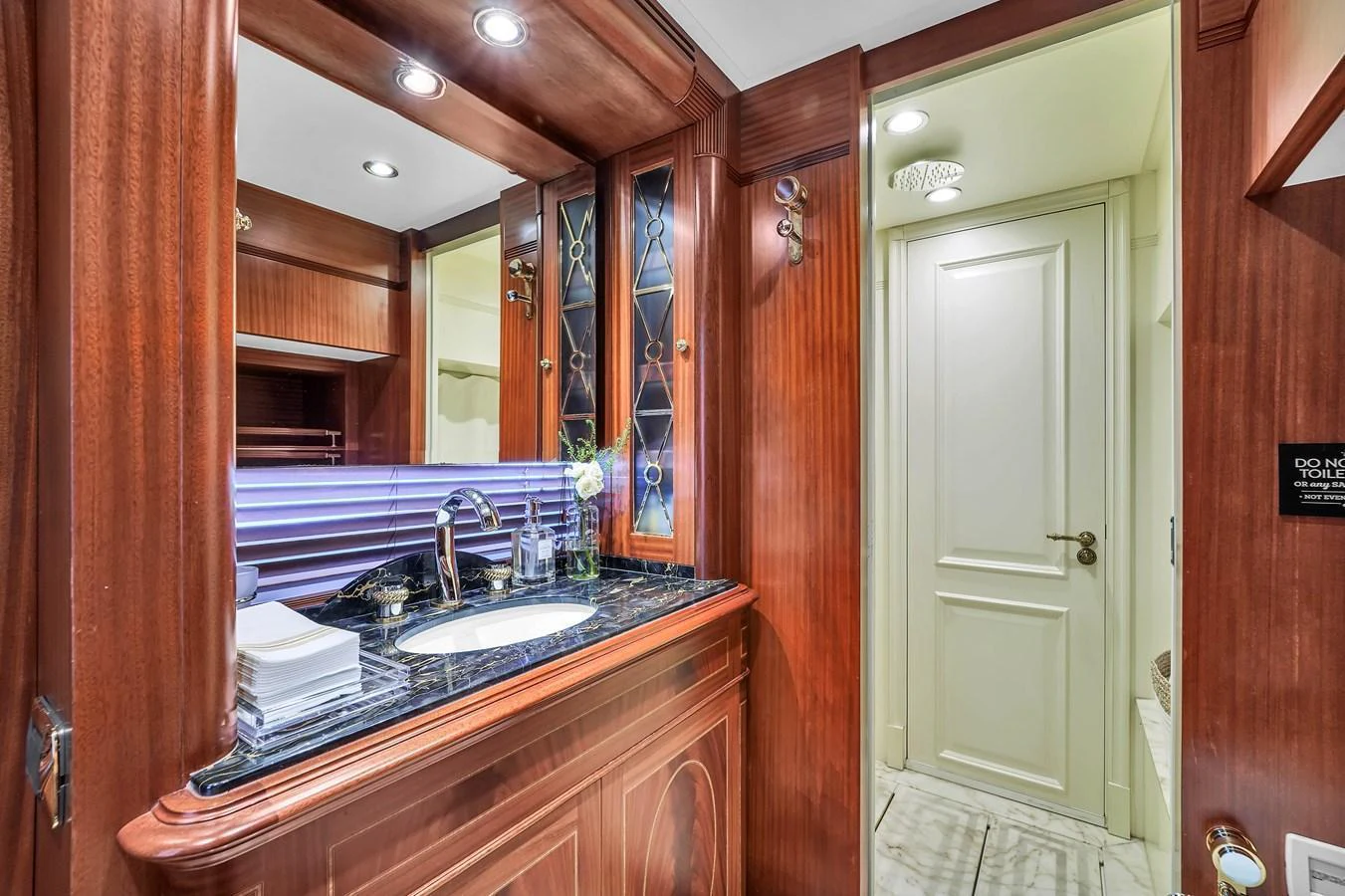 The yacht's bathroom features elegant wood paneling and a luxurious marble countertop. aboard AZIMUT GRANDE 105 Yacht for Sale