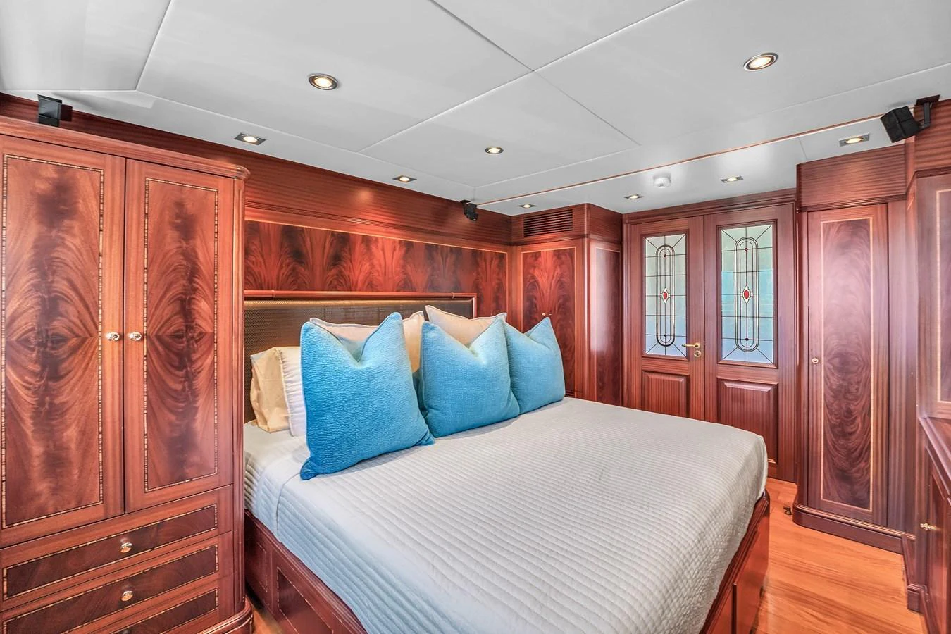 The stateroom features rich wood paneling and a comfortable bed with plush blue pillows. aboard AZIMUT GRANDE 105 Yacht for Sale