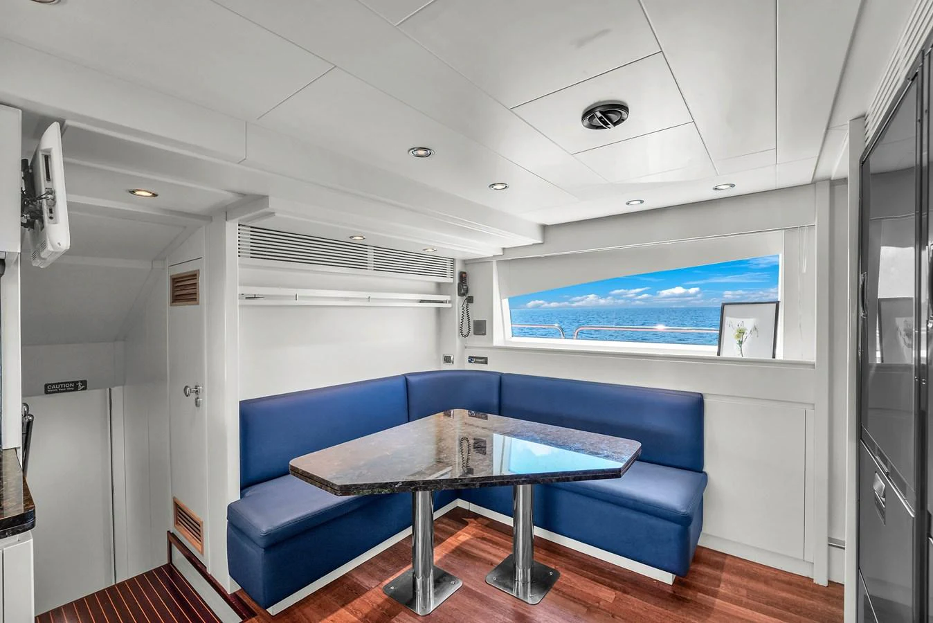 The yacht's dining area features a sleek table with comfortable blue seating and a panoramic window view. aboard AZIMUT GRANDE 105 Yacht for Sale