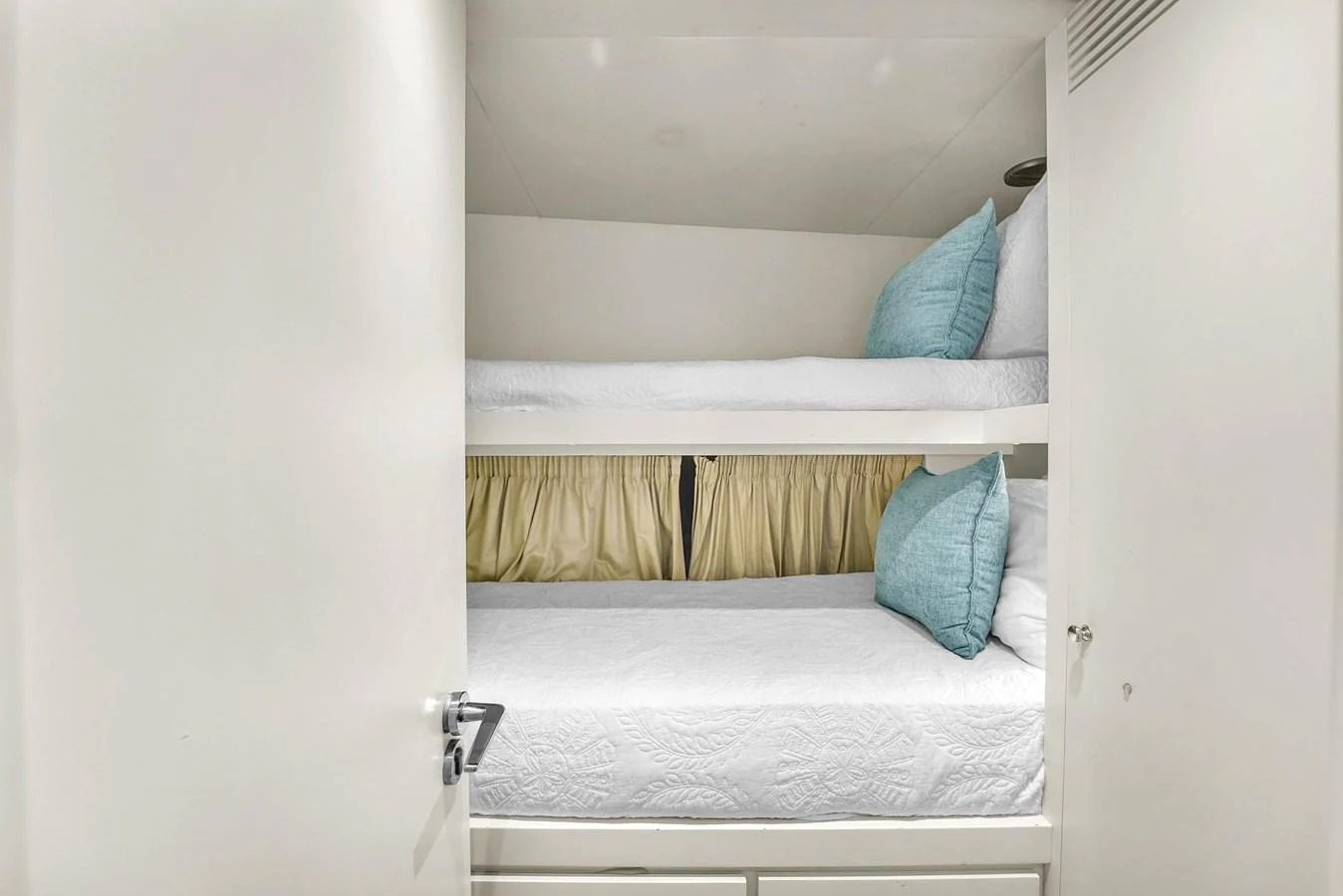 The cozy bunk cabin features two neatly arranged beds with light blue pillows and a curtain for privacy. aboard AZIMUT GRANDE 105 Yacht for Sale