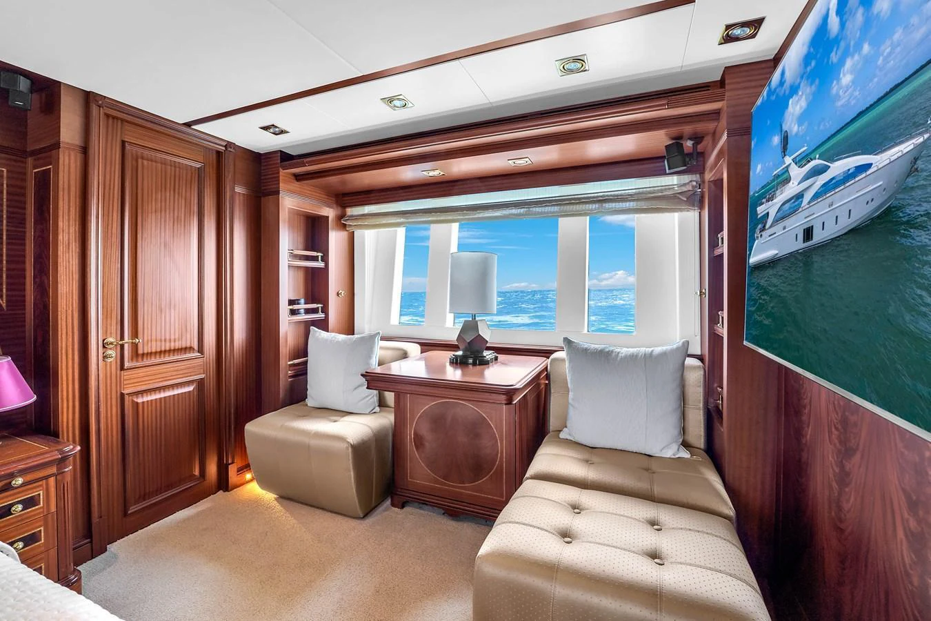 The yacht's lounge features plush seating, rich wooden paneling, and a large window with an ocean view. aboard AZIMUT GRANDE 105 Yacht for Sale