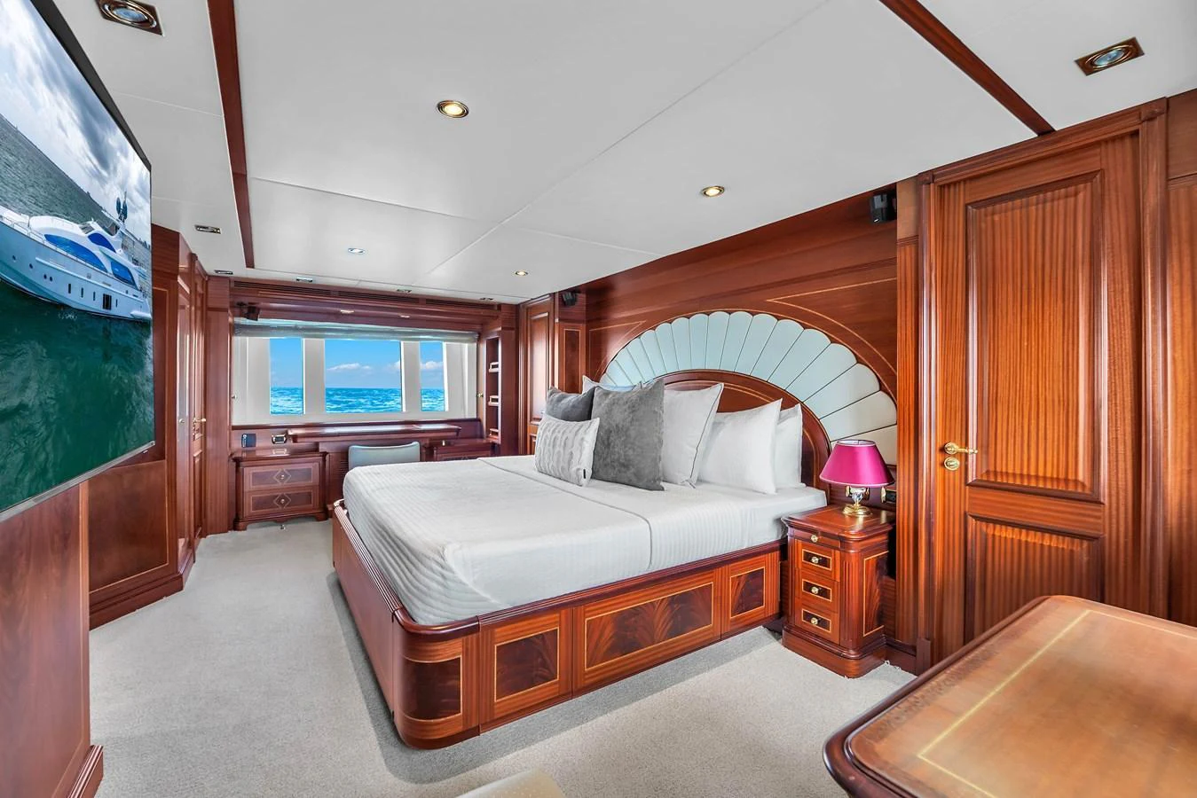 The master stateroom features luxurious wood paneling, a large bed, and a scenic view through the windows. aboard AZIMUT GRANDE 105 Yacht for Sale