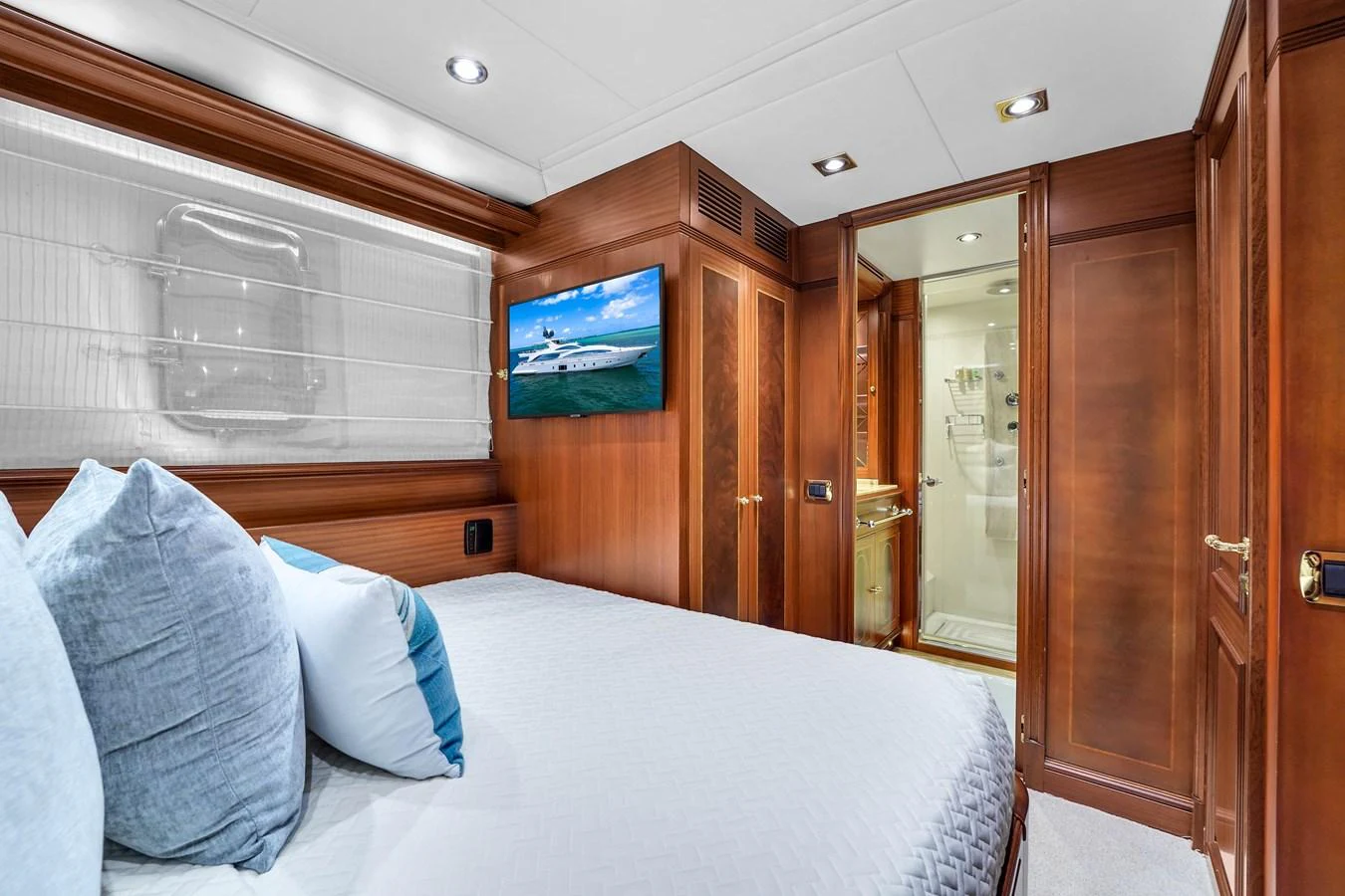 A luxurious stateroom featuring a comfortable bed, wood paneling, and an ensuite bathroom. aboard AZIMUT GRANDE 105 Yacht for Sale