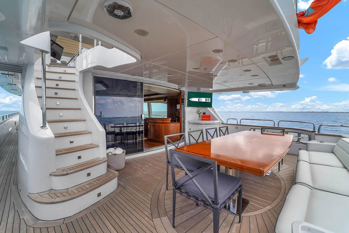 The aft deck features a spacious dining area with a polished wooden table and comfortable seating, perfect for alfresco dining. aboard AZIMUT GRANDE 105 Yacht for Sale