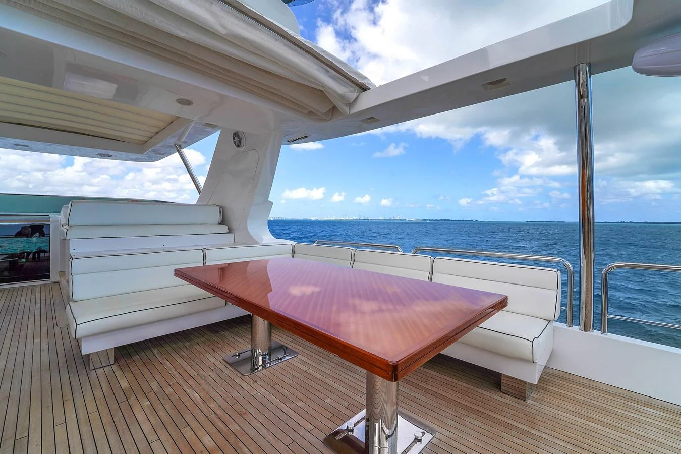 The aft deck features a spacious seating area with a polished wooden table, offering stunning views of the open sea. aboard AZIMUT GRANDE 105 Yacht for Sale