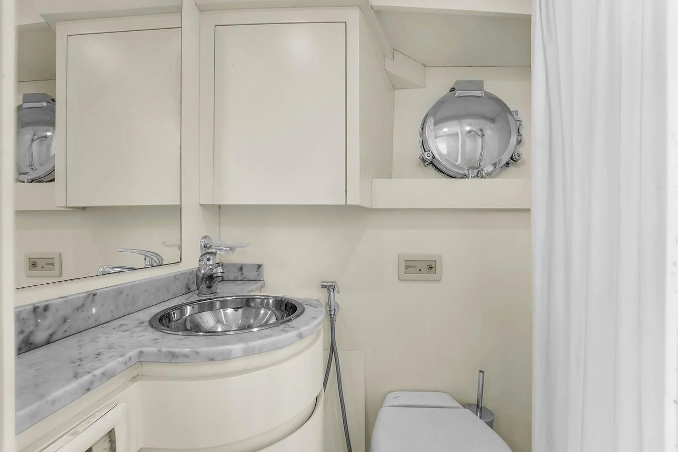 A pristine yacht bathroom featuring a sleek sink and a porthole window. aboard AZIMUT GRANDE 105 Yacht for Sale