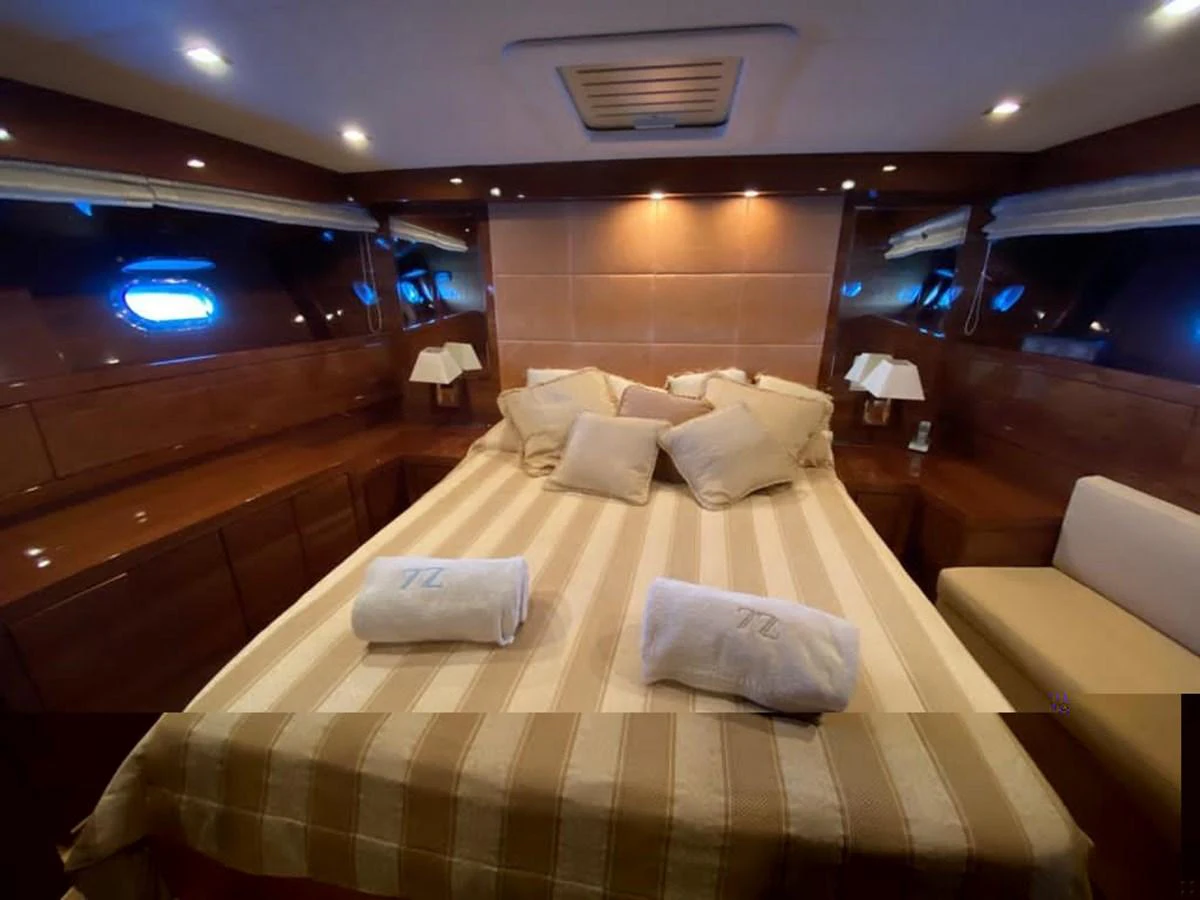 The stateroom features a cozy bed with plush pillows and elegant wooden finishes. aboard SEVEN ZERO Yacht for Sale