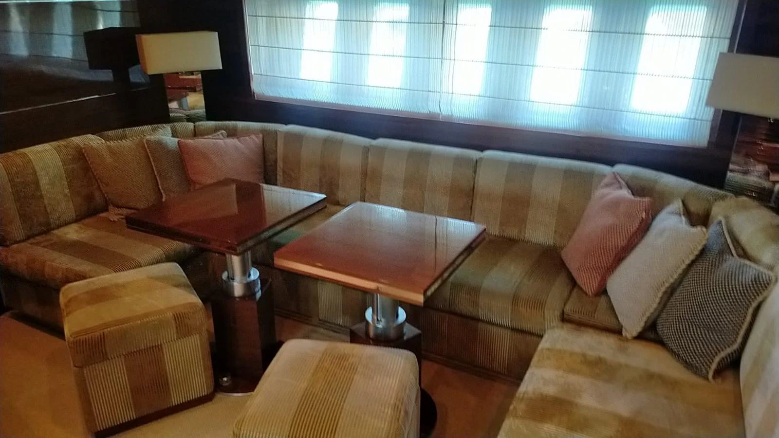 The salon features a cozy seating area with striped upholstery and wooden tables, perfect for relaxation. aboard SEVEN ZERO Yacht for Sale