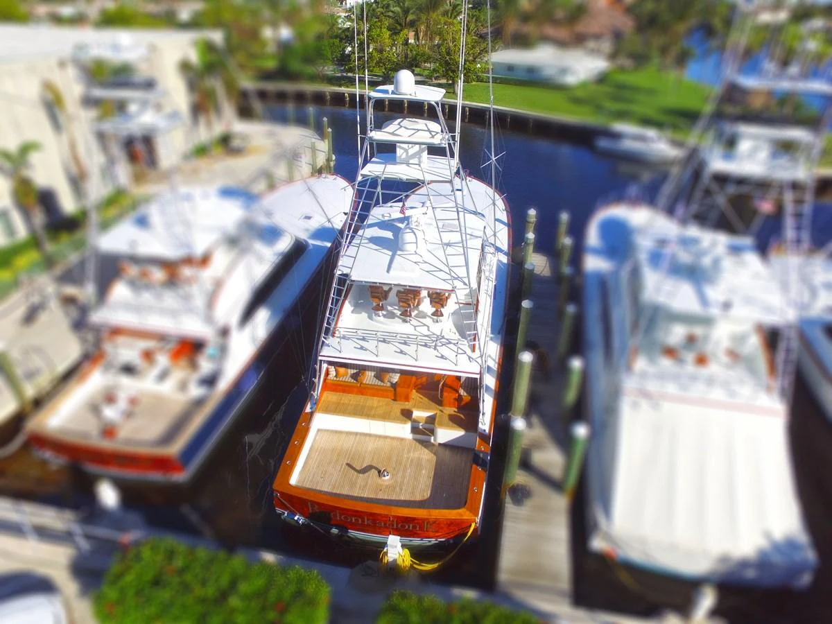 The yacht is docked at a marina, showcasing its spacious aft deck with a wooden finish. aboard REMAIN CALM Yacht for Sale