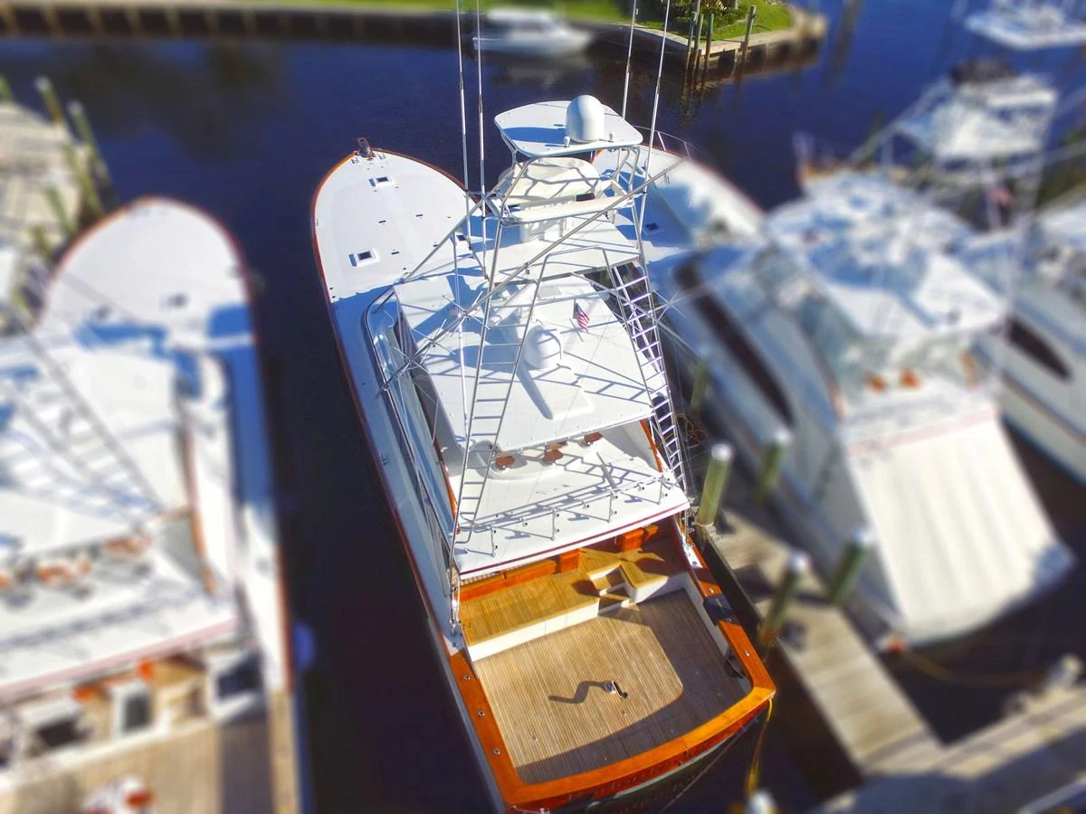 A sleek yacht is docked at a marina, showcasing its spacious aft deck and towering flybridge. aboard REMAIN CALM Yacht for Sale