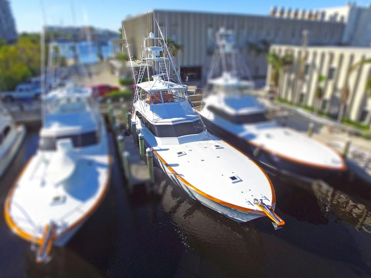 A sleek yacht is docked at a marina, surrounded by other vessels. aboard REMAIN CALM Yacht for Sale