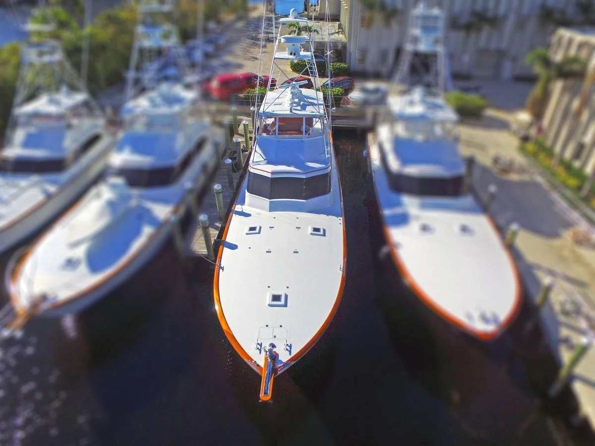 A sleek yacht is docked alongside other vessels in a marina, showcasing its streamlined design and spacious deck. aboard REMAIN CALM Yacht for Sale