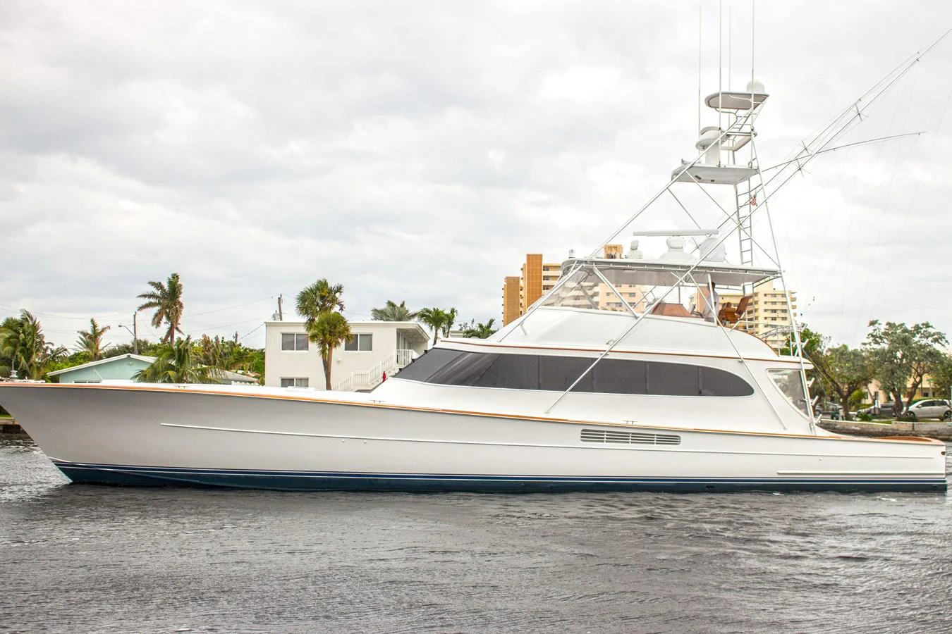 A sleek and elegant yacht is showcased on calm waters with a backdrop of palm trees and buildings. aboard REMAIN CALM Yacht for Sale