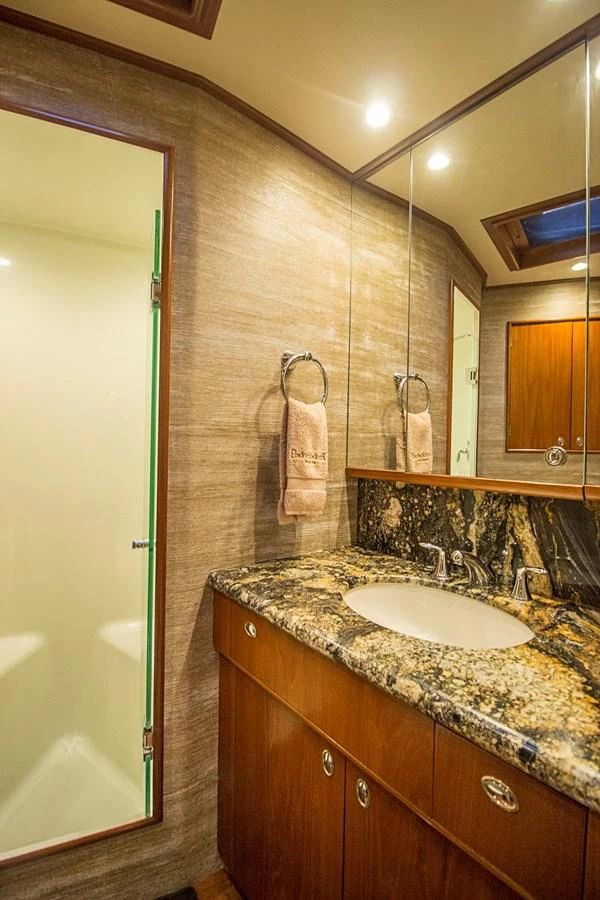 The yacht's bathroom features a luxurious granite countertop and elegant wood cabinetry. aboard REMAIN CALM Yacht for Sale