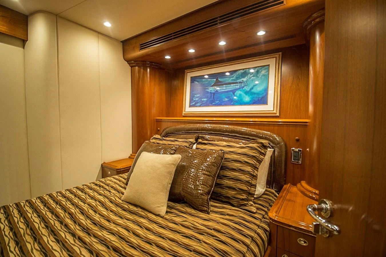 A luxurious stateroom with elegant wood paneling and a comfortable bed adorned with decorative pillows. aboard REMAIN CALM Yacht for Sale