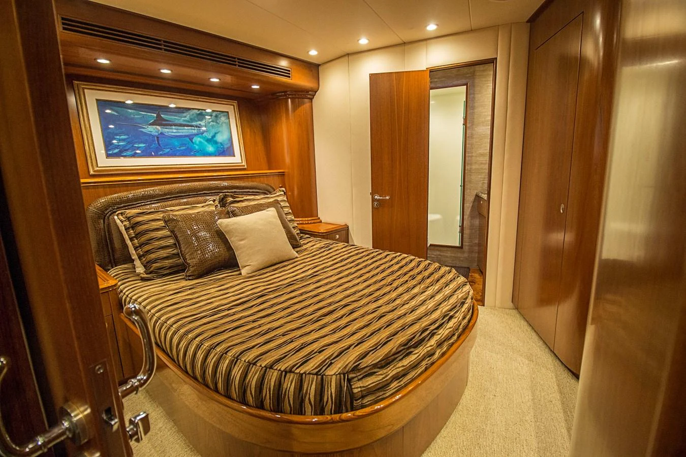 A cozy stateroom featuring a comfortable bed with striped bedding and warm wooden finishes. aboard REMAIN CALM Yacht for Sale