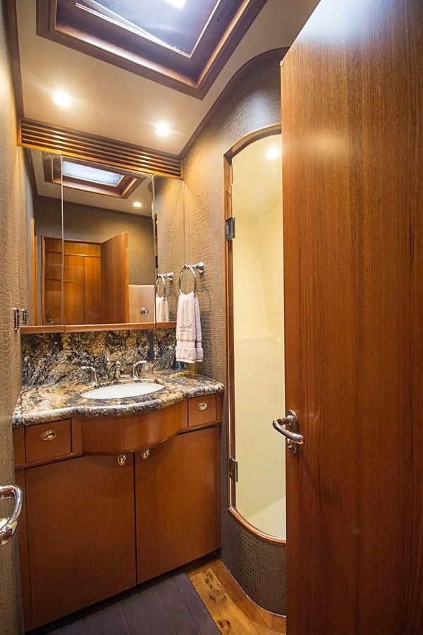 The yacht's bathroom features elegant wood finishes and a marble countertop. aboard REMAIN CALM Yacht for Sale