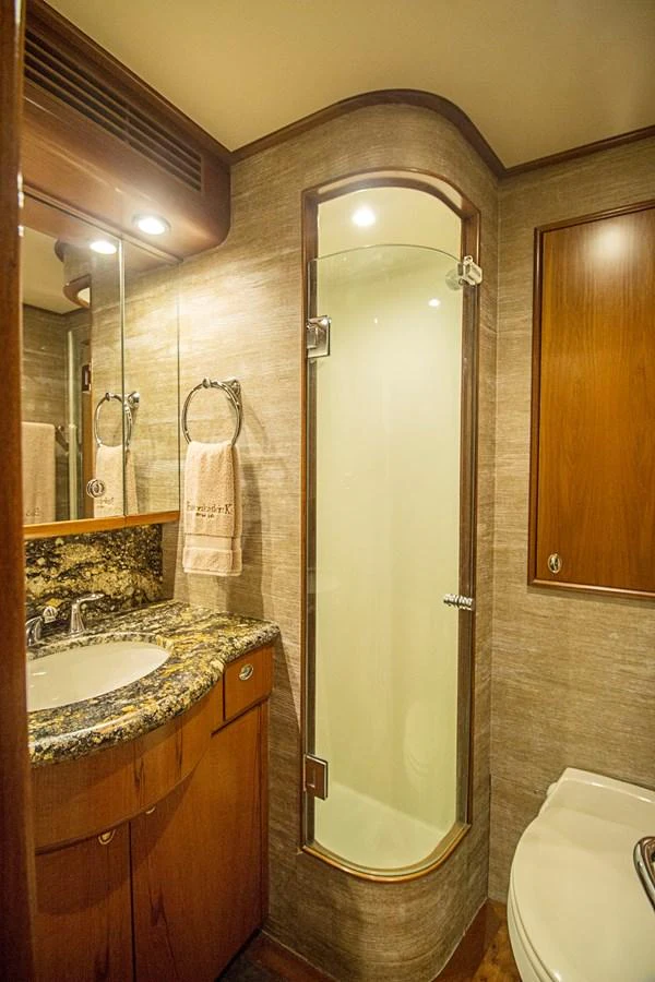 A well-appointed yacht bathroom featuring a glass-enclosed shower and elegant wood finishes. aboard REMAIN CALM Yacht for Sale