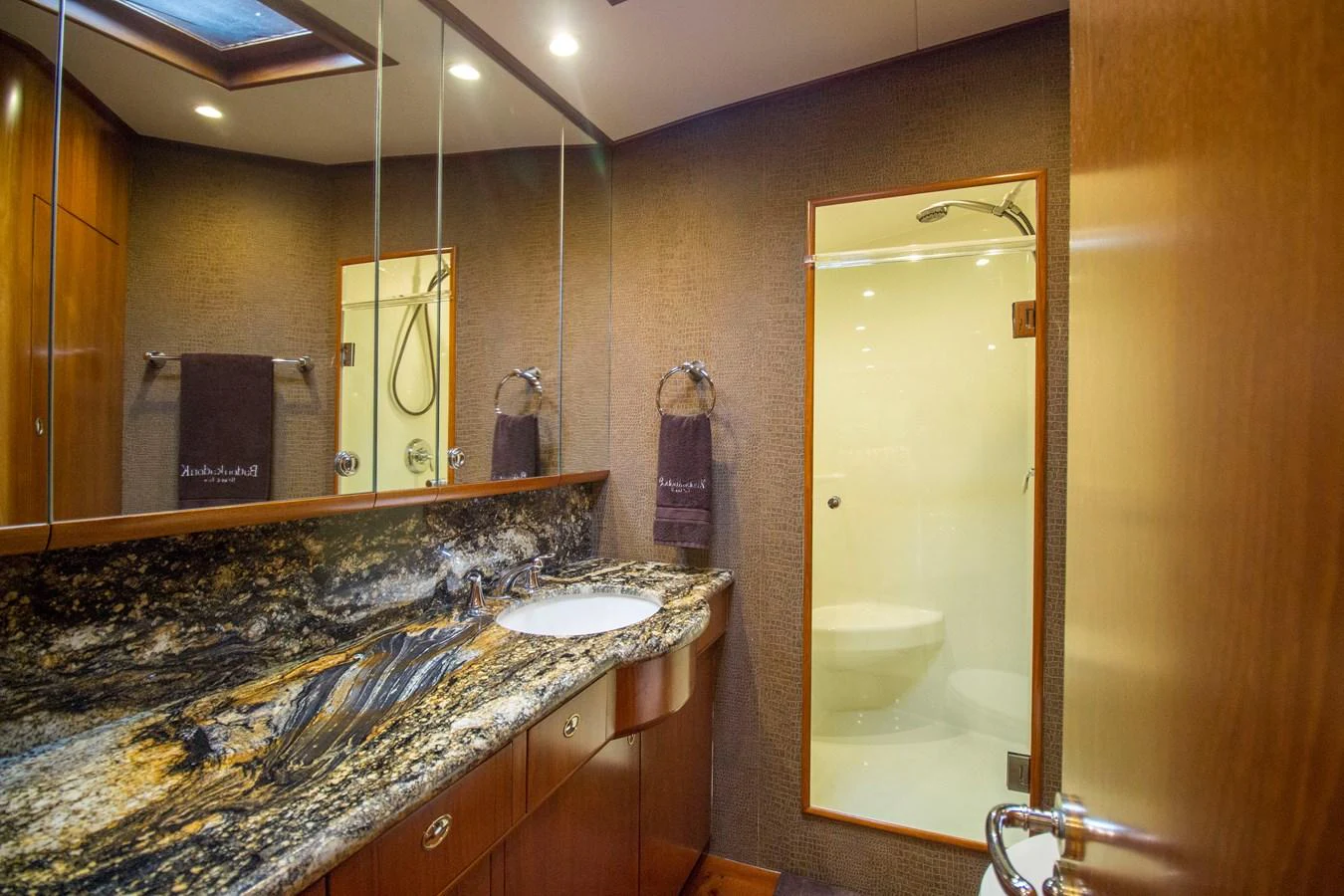 The yacht's bathroom features elegant wood cabinetry and a luxurious marble countertop. aboard REMAIN CALM Yacht for Sale