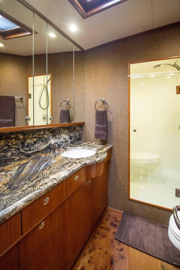 The yacht's bathroom features a luxurious marble countertop and a spacious shower area. aboard REMAIN CALM Yacht for Sale