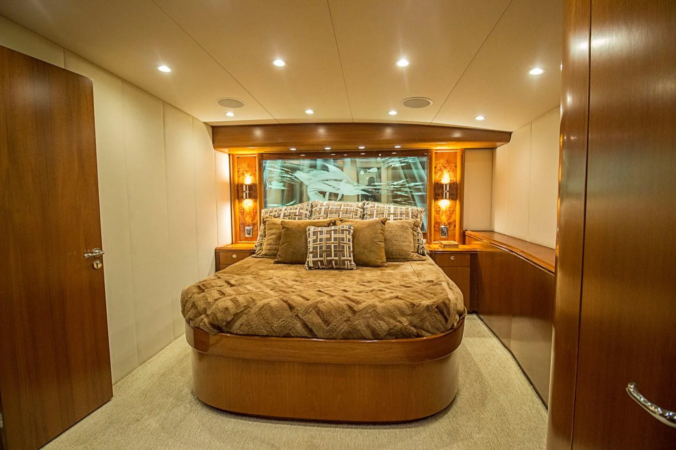 The master stateroom features a luxurious bed with warm wood finishes and ambient lighting. aboard REMAIN CALM Yacht for Sale