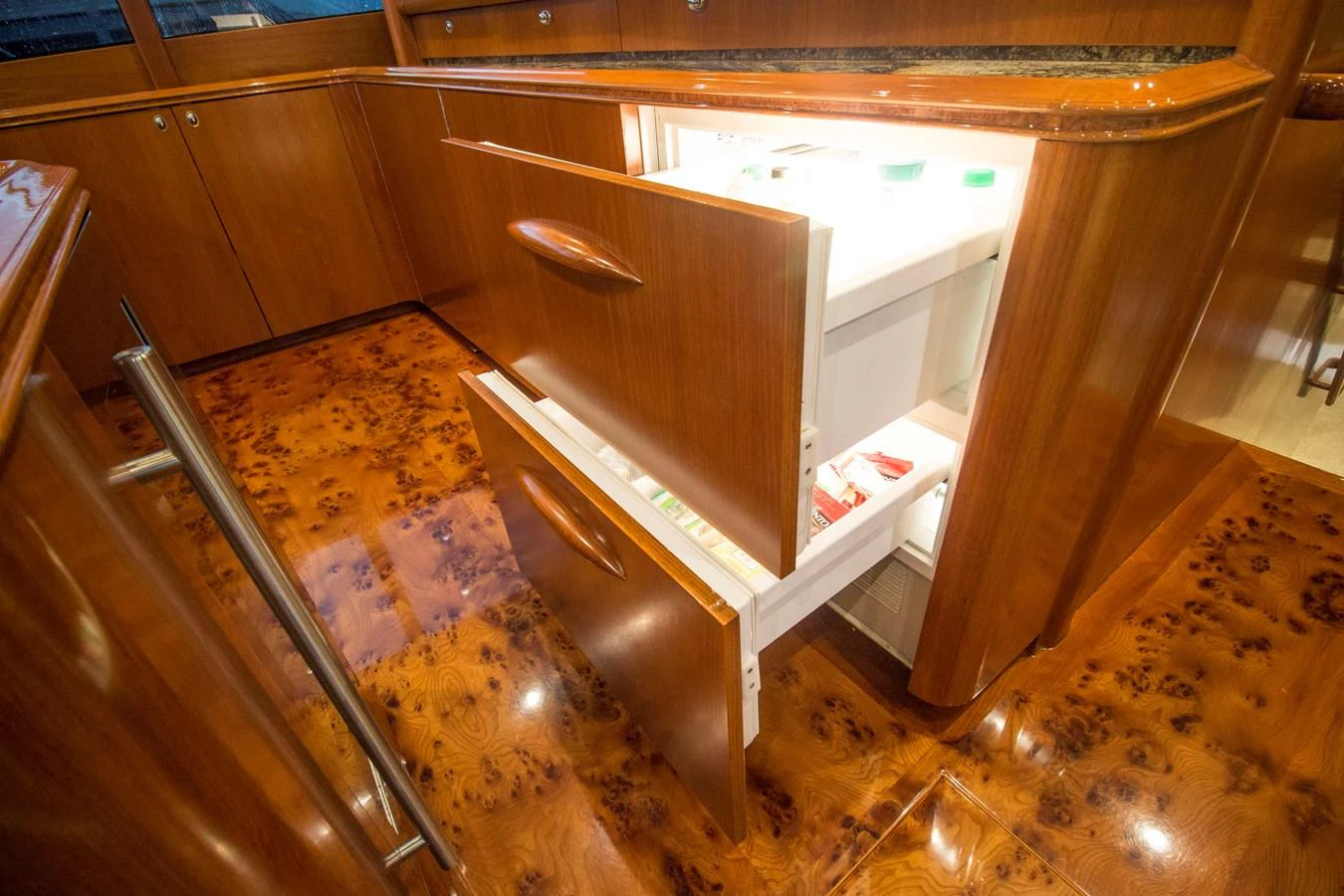 The yacht's galley features luxurious wood cabinetry and a built-in refrigerator drawer. aboard REMAIN CALM Yacht for Sale