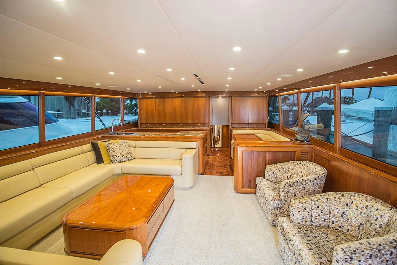 The salon features plush seating, a wooden coffee table, and large windows for natural light. aboard REMAIN CALM Yacht for Sale