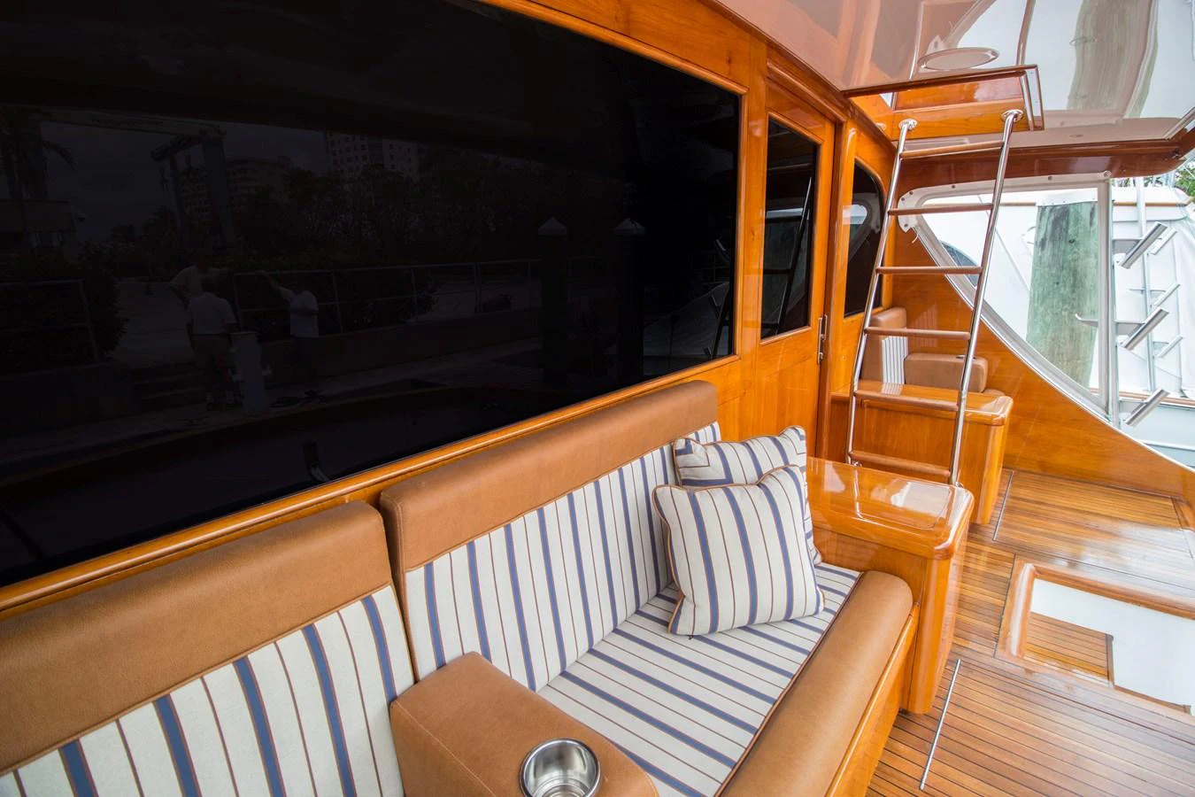 The aft deck features a comfortable seating area with striped cushions and polished wooden finishes. aboard REMAIN CALM Yacht for Sale