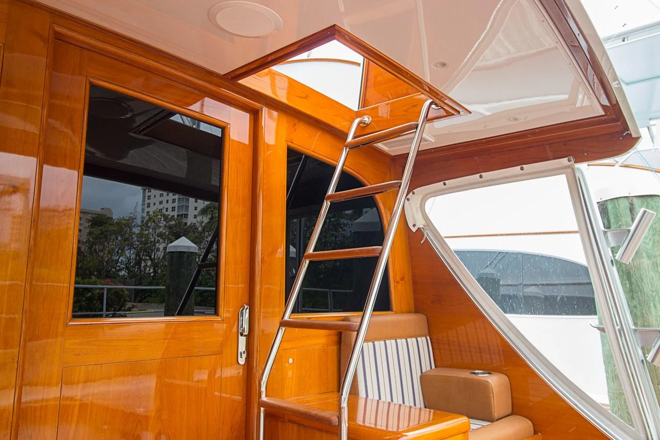 A polished wooden interior with a sleek metal staircase leading to an upper deck. aboard REMAIN CALM Yacht for Sale