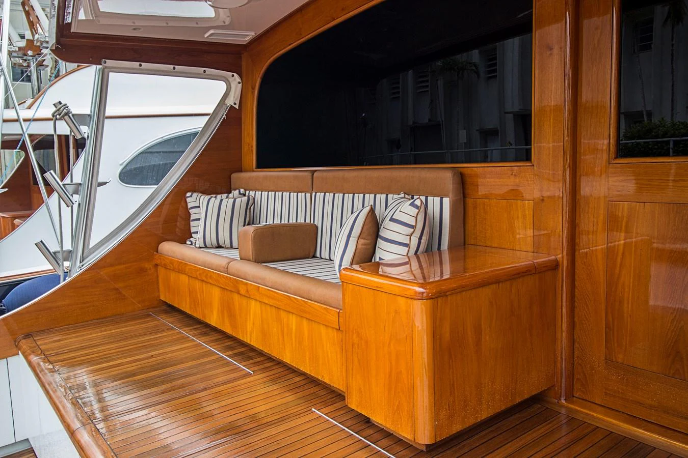 The yacht's aft deck features a polished wooden seating area with striped cushions, offering a cozy and inviting space for relaxation. aboard REMAIN CALM Yacht for Sale