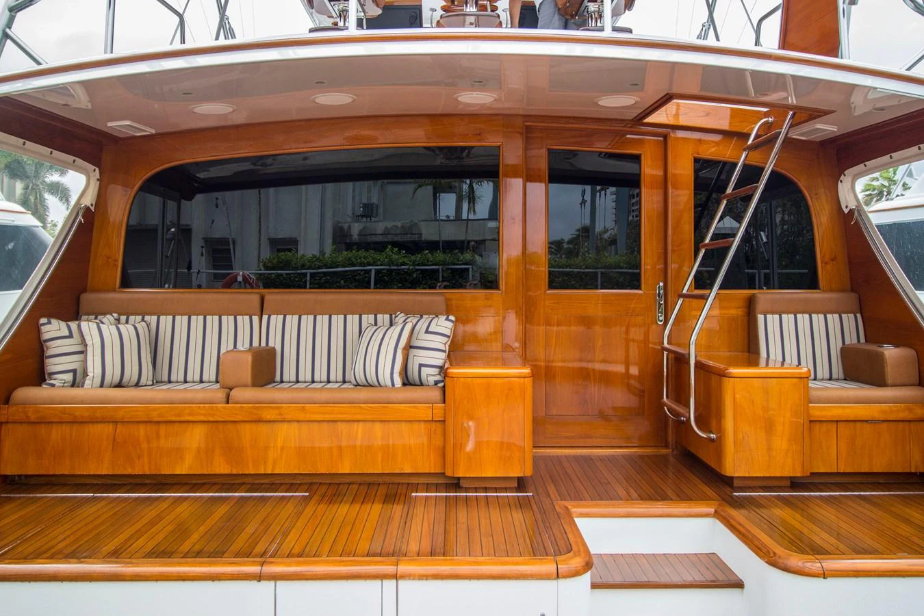 The aft deck features luxurious wooden seating with striped cushions, perfect for relaxation. aboard REMAIN CALM Yacht for Sale