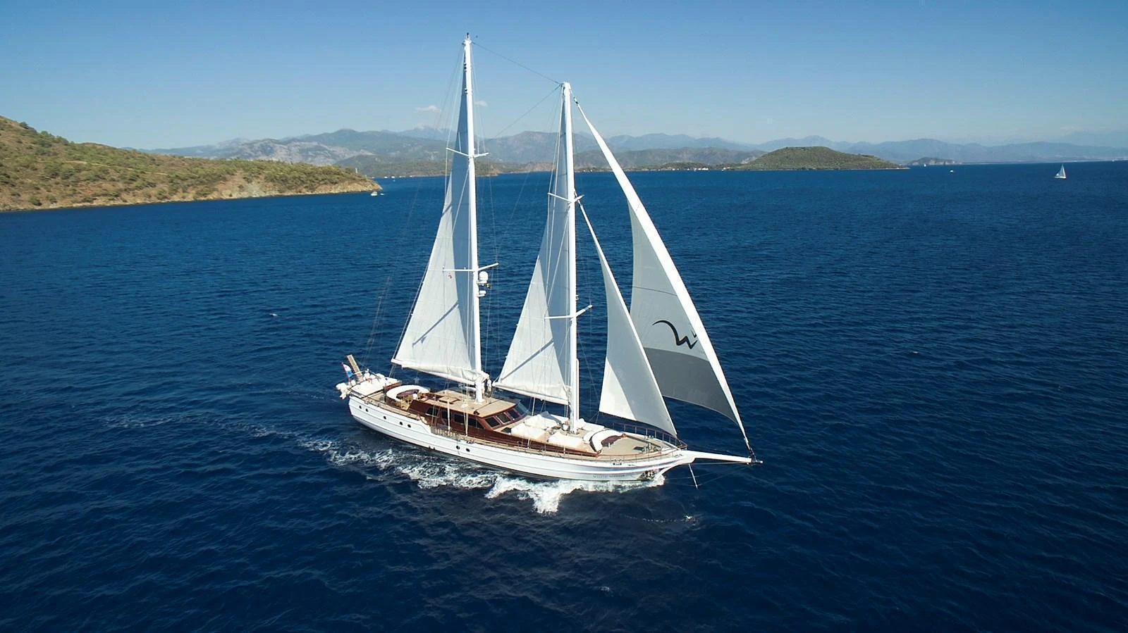 A stunning sailing yacht glides gracefully on the open sea under clear blue skies. aboard WHITE WINGS Yacht for Sale