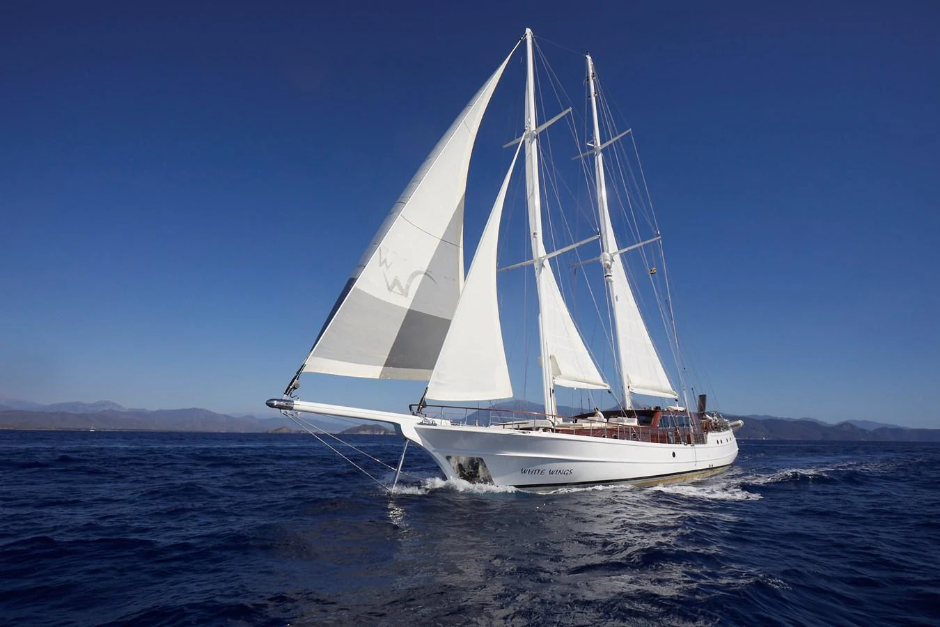 A stunning sailing yacht glides gracefully across the open sea under full sail. aboard WHITE WINGS Yacht for Sale