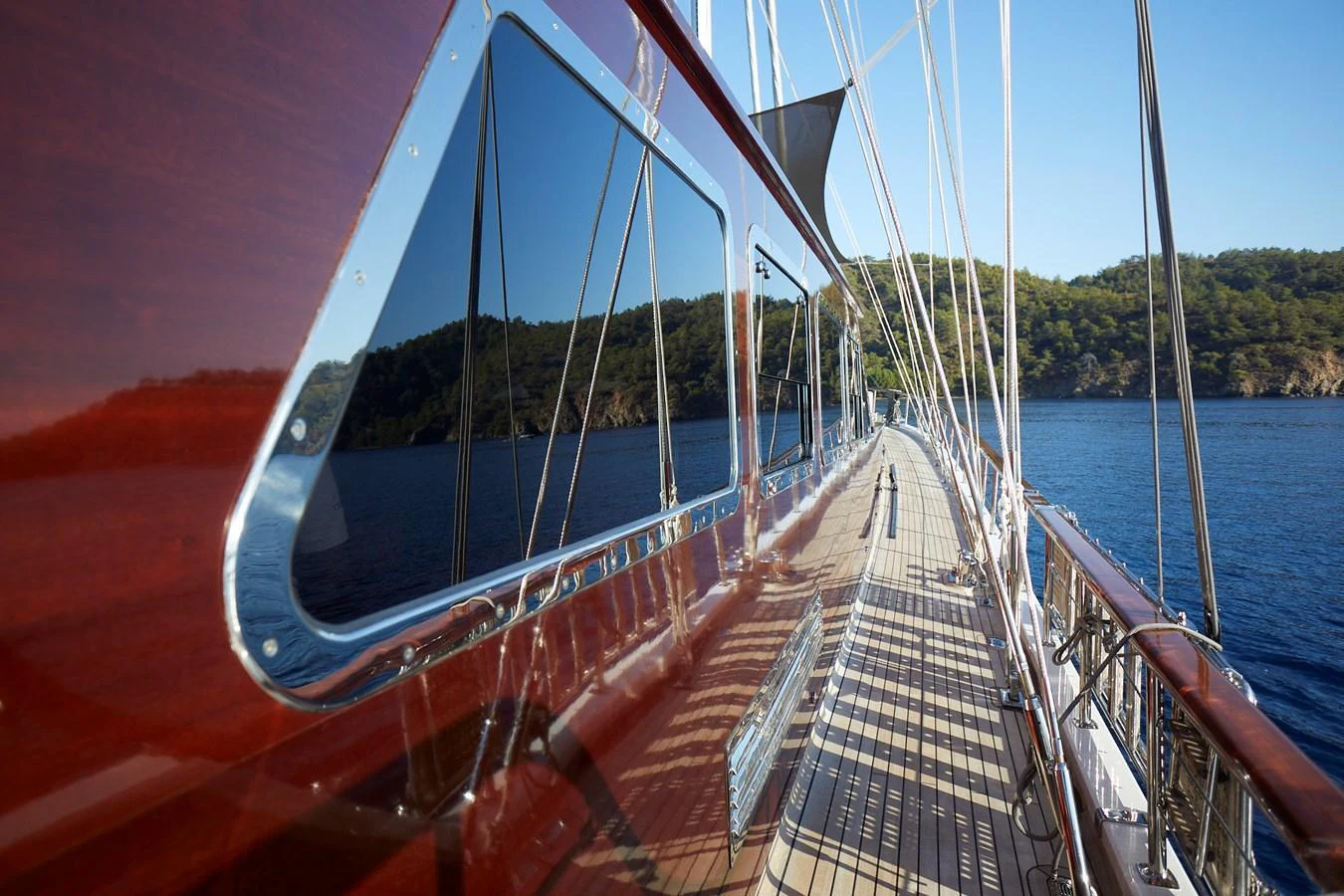 A sleek yacht deck with polished wood and scenic reflections on the windows. aboard WHITE WINGS Yacht for Sale