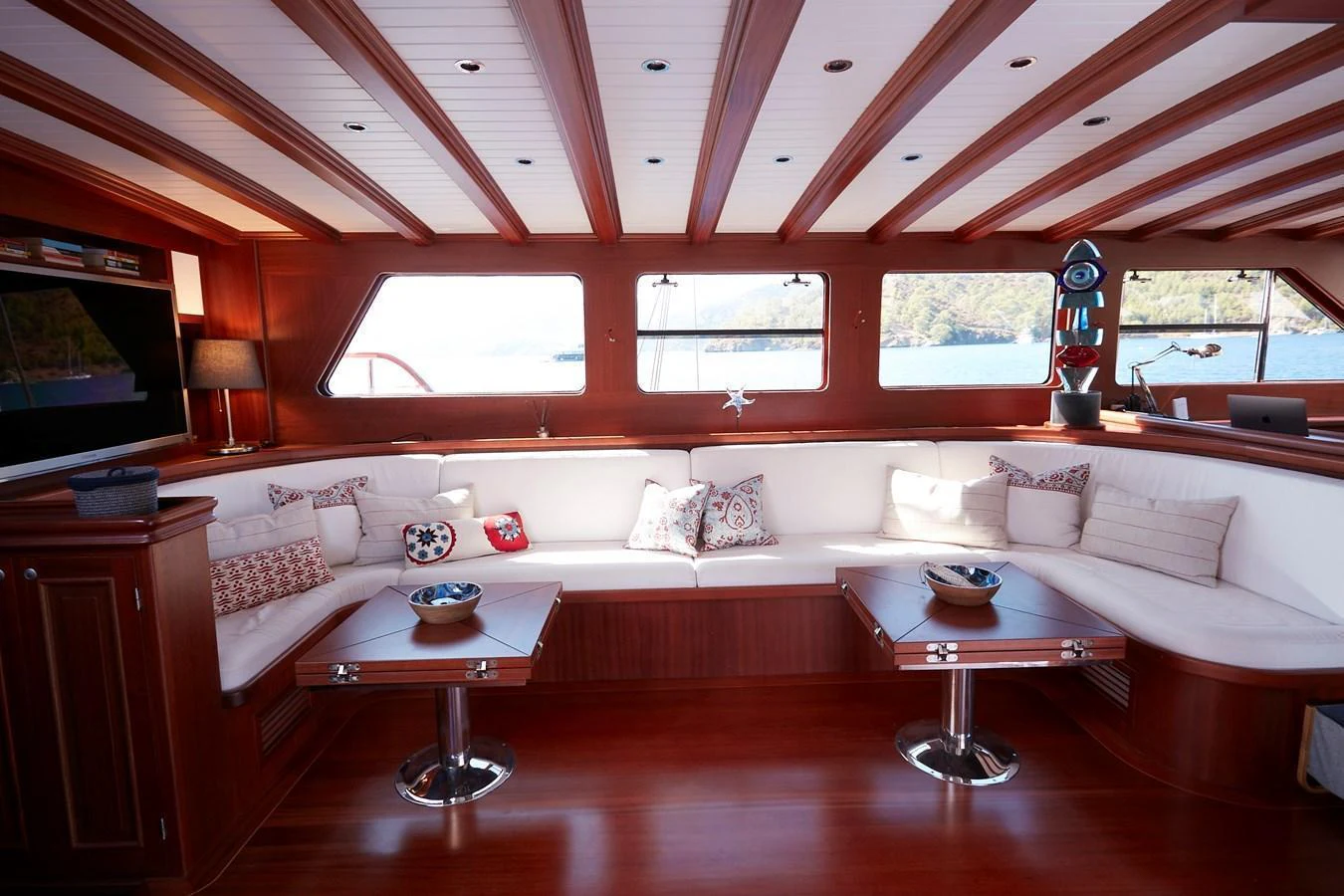 The yacht's salon features elegant wood paneling, plush seating, and large windows offering scenic views. aboard WHITE WINGS Yacht for Sale