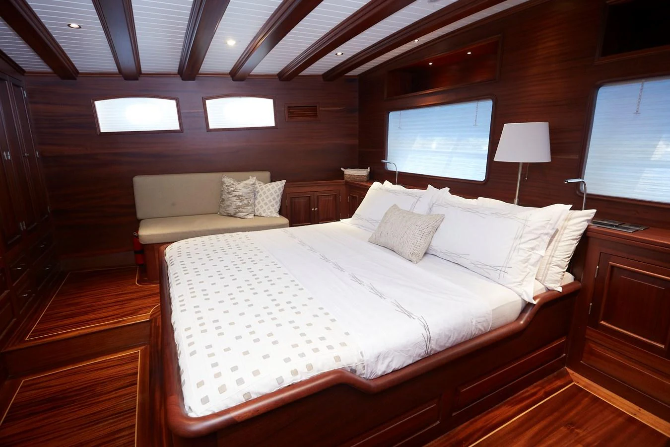 The master stateroom features a luxurious bed with elegant wood finishes and ample natural light. aboard WHITE WINGS Yacht for Sale