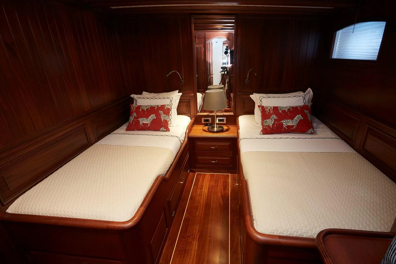 The twin stateroom features rich wood paneling and comfortable twin beds with decorative pillows. aboard WHITE WINGS Yacht for Sale